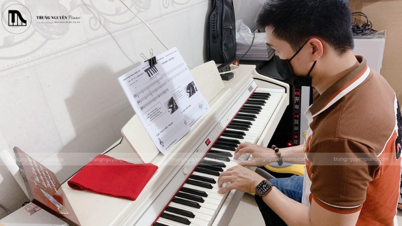 Một người đang chơi thử và lắng nghe âm thanh đàn piano một cách chăm chú