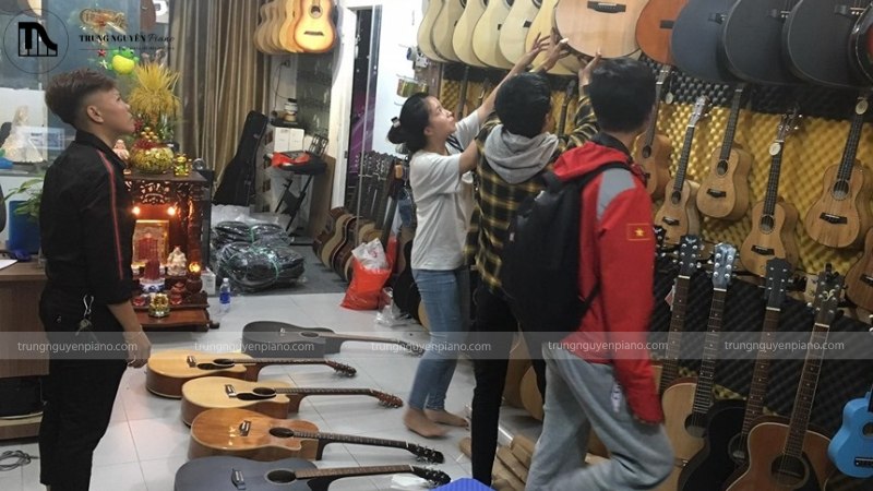 Nhân viên tư vấn về đàn bass trong một cửa hàng nhạc cụ sáng sủa, chuyên nghiệp