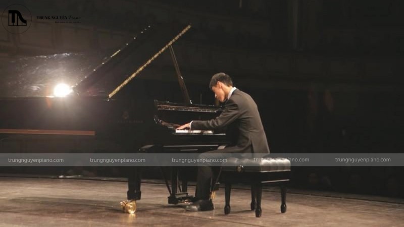 Nghệ sĩ piano đang biểu diễn trên sân khấu, tập trung vào sự biểu cảm và tư thế chân trên pedal