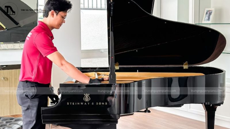 Kỹ thuật viên cẩn thận lên dây một cây đàn upright piano trong phòng khách