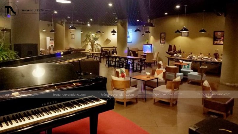 Một cây đàn piano upright được đặt trang trọng trong góc quán cafe acoustic