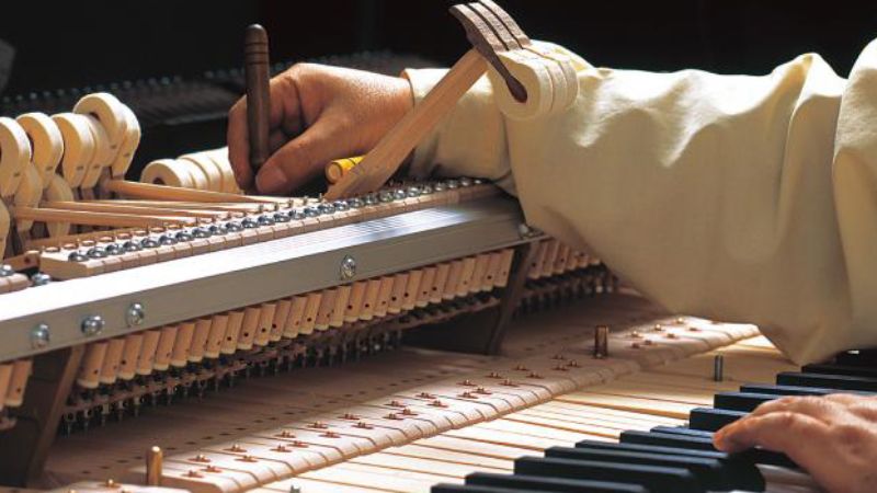 Kỹ thuật viên đang lên dây đàn, đảm bảo âm thanh ổn định