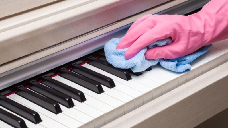 Lau phím đàn đúng cách với khăn mềm, ẩm nhẹ để tránh hư hại do hóa chất