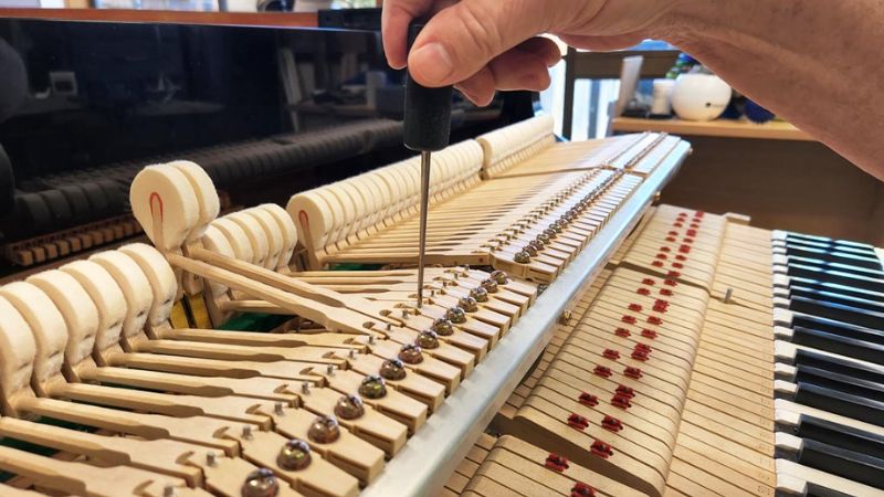 Kỹ thuật viên kiểm tra chi tiết bộ máy action bên trong đàn piano