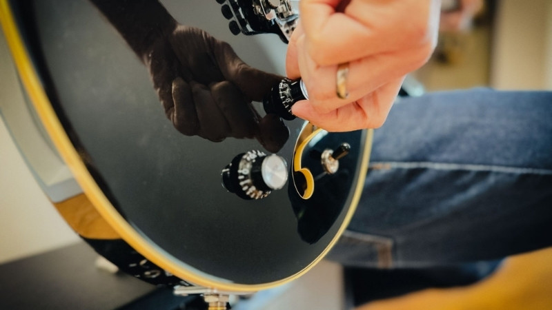 Kiểm tra núm vặn guitar điện bằng cách xoay từng núm và lắng nghe tiếng lạo xạo