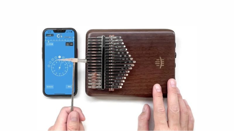 Người chơi dùng búa chỉnh nhẹ các phím kalimba để đạt âm chuẩn