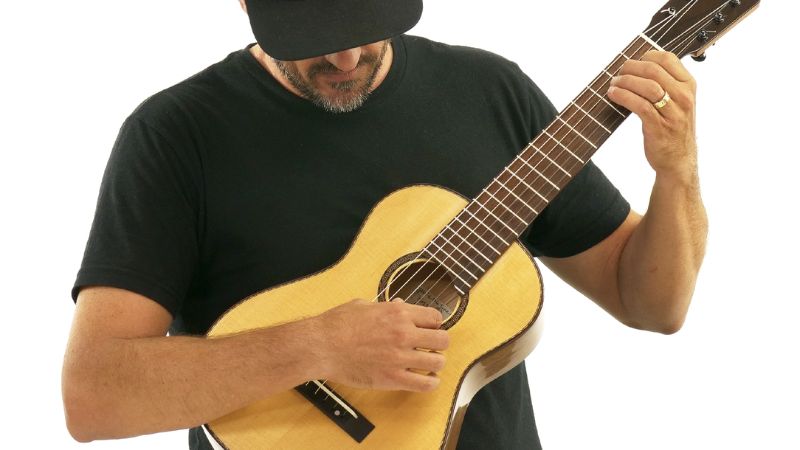 Tay phải đặt thoải mái lên thùng đàn Guitalele để gảy dây, tay trái linh hoạt bấm phím trên cần đàn